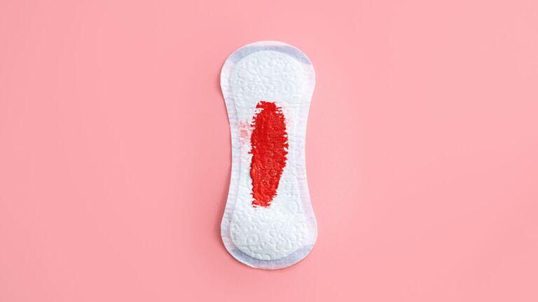 absorvente com um pouco de sangue em fundo rosa