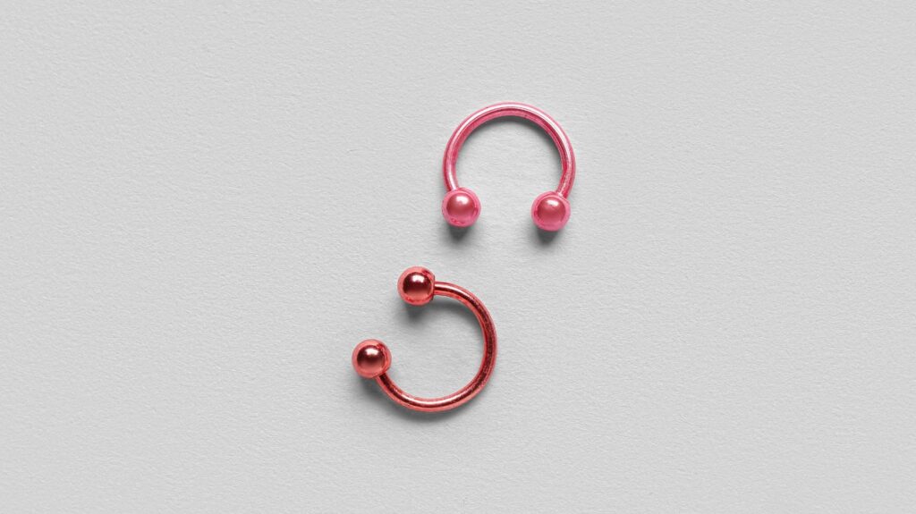 piercing rosa e vermelho em fundo cinza