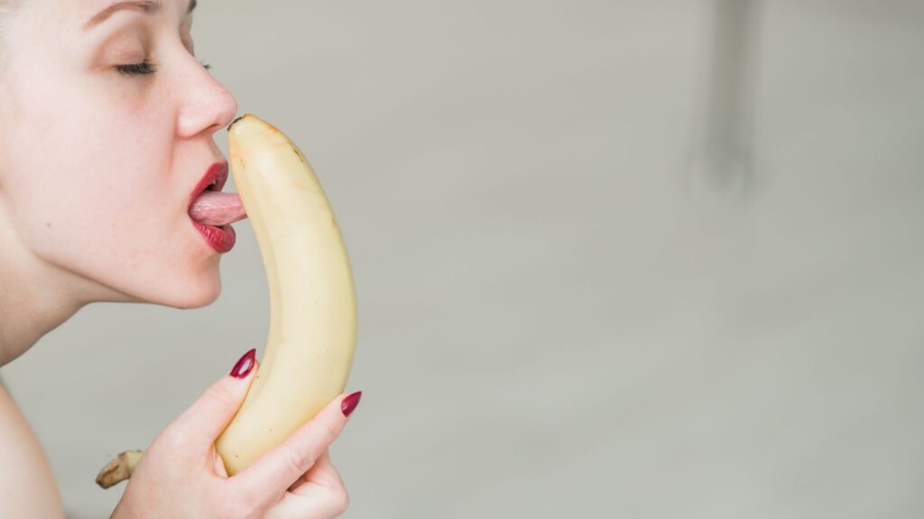 mulher lambendo banana remetendo a sexo oral