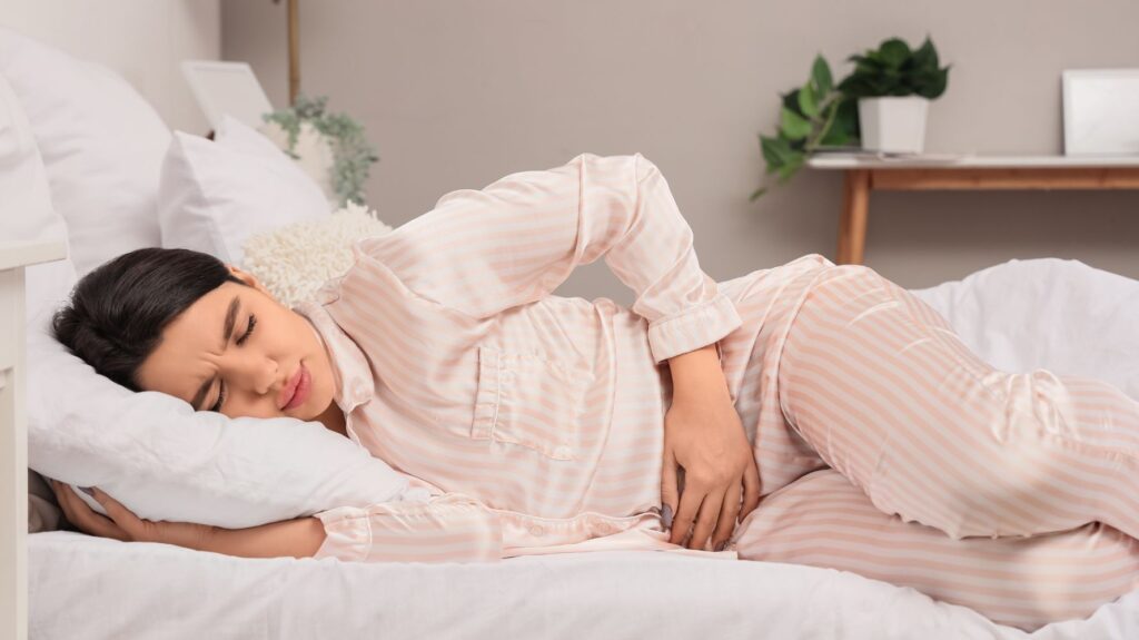 mulher na cama com cólica menstrual
