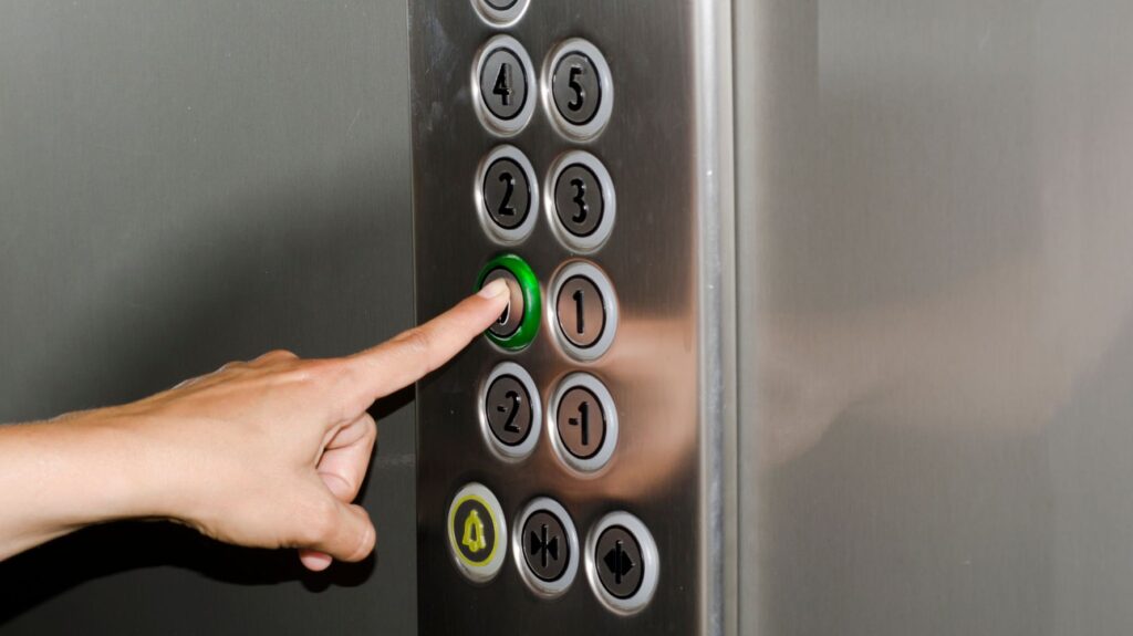 mão apertando botão de elevador