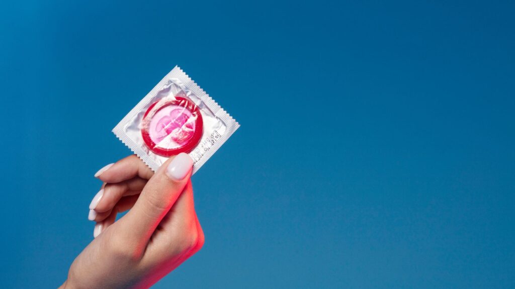 mão segurando camisinha