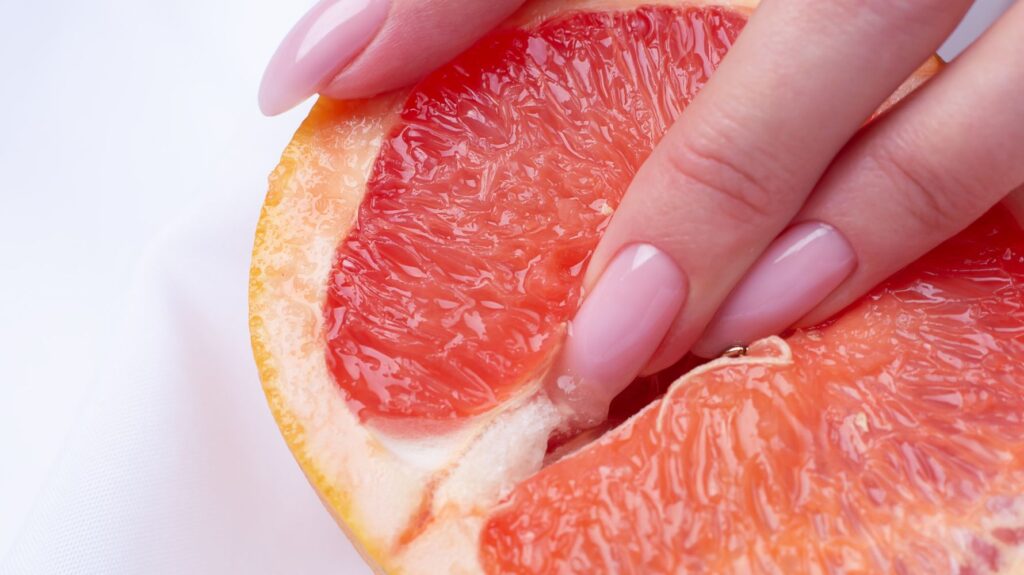 dedos de mulher em laranja para remeter à estímulo no clitóris